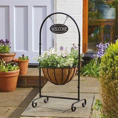 Plant in portable hanging basket with welcome sign above it