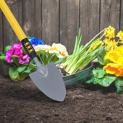 Garden hand spade, in soil with flowers