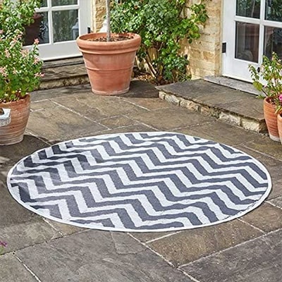 White and grey zig zag garden circular rug, with plants around it in a patio.